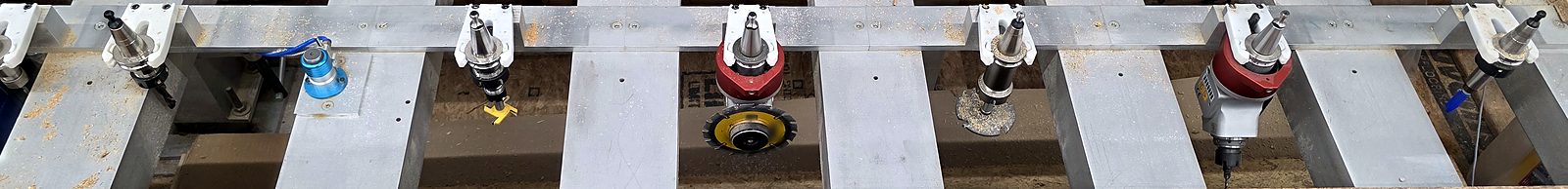 Tool rack with toolholders, a probe, and aggregate heads, including a saw blade head, on the 18-foot CNC router