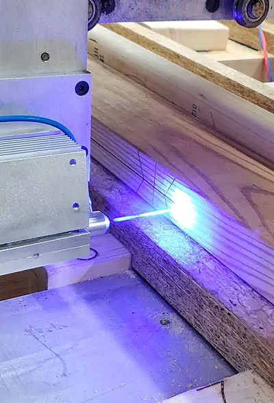 Laser line marking a cut position on lumber on the CNC router