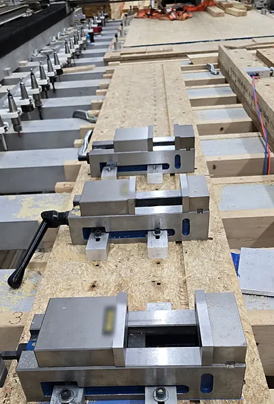 Three machine vises lined up on the router table, with the tool-changer rack behind
