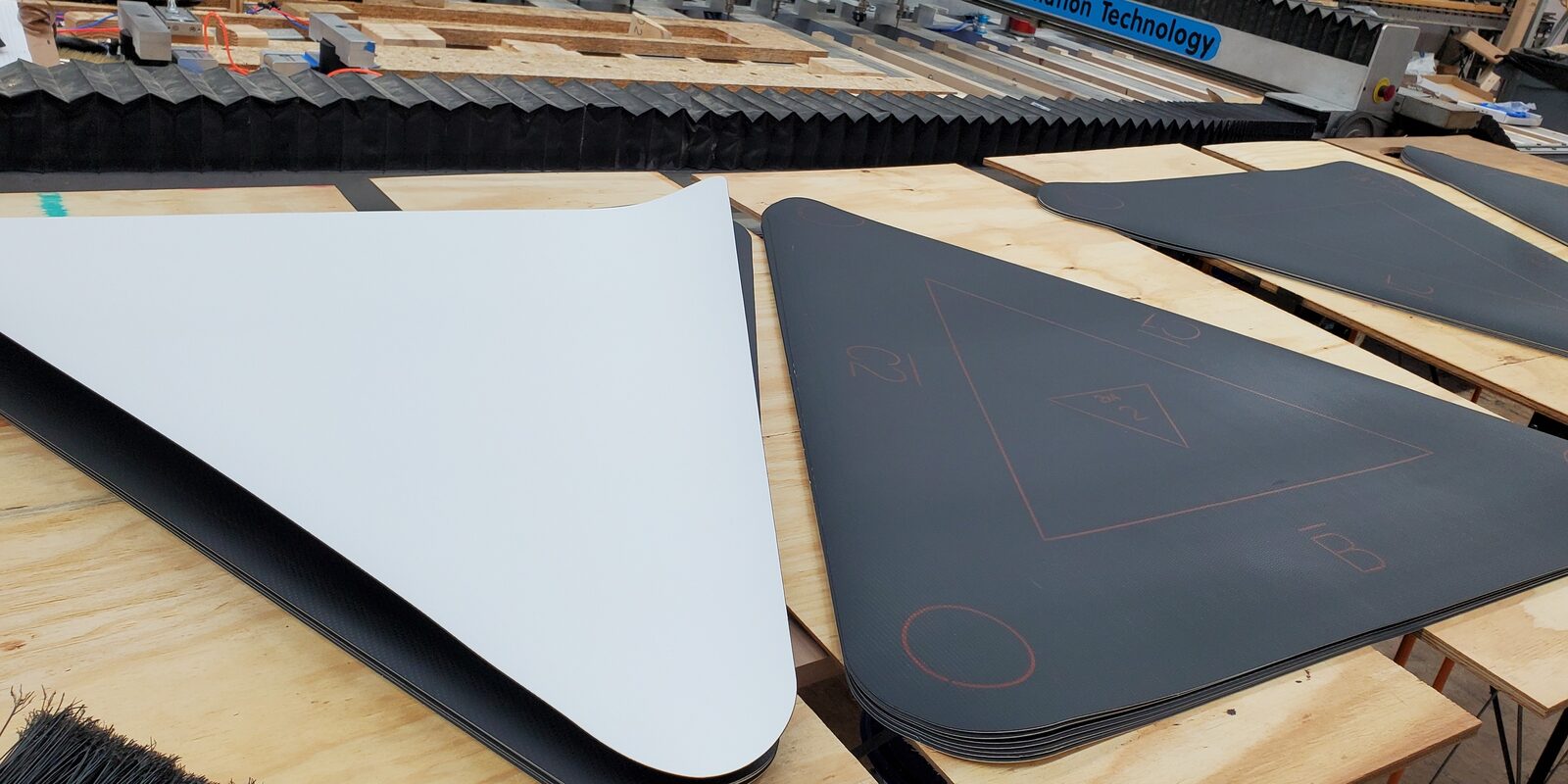 Finished white and black TPO membrane pieces, marked with part labels and cut with rounded corners